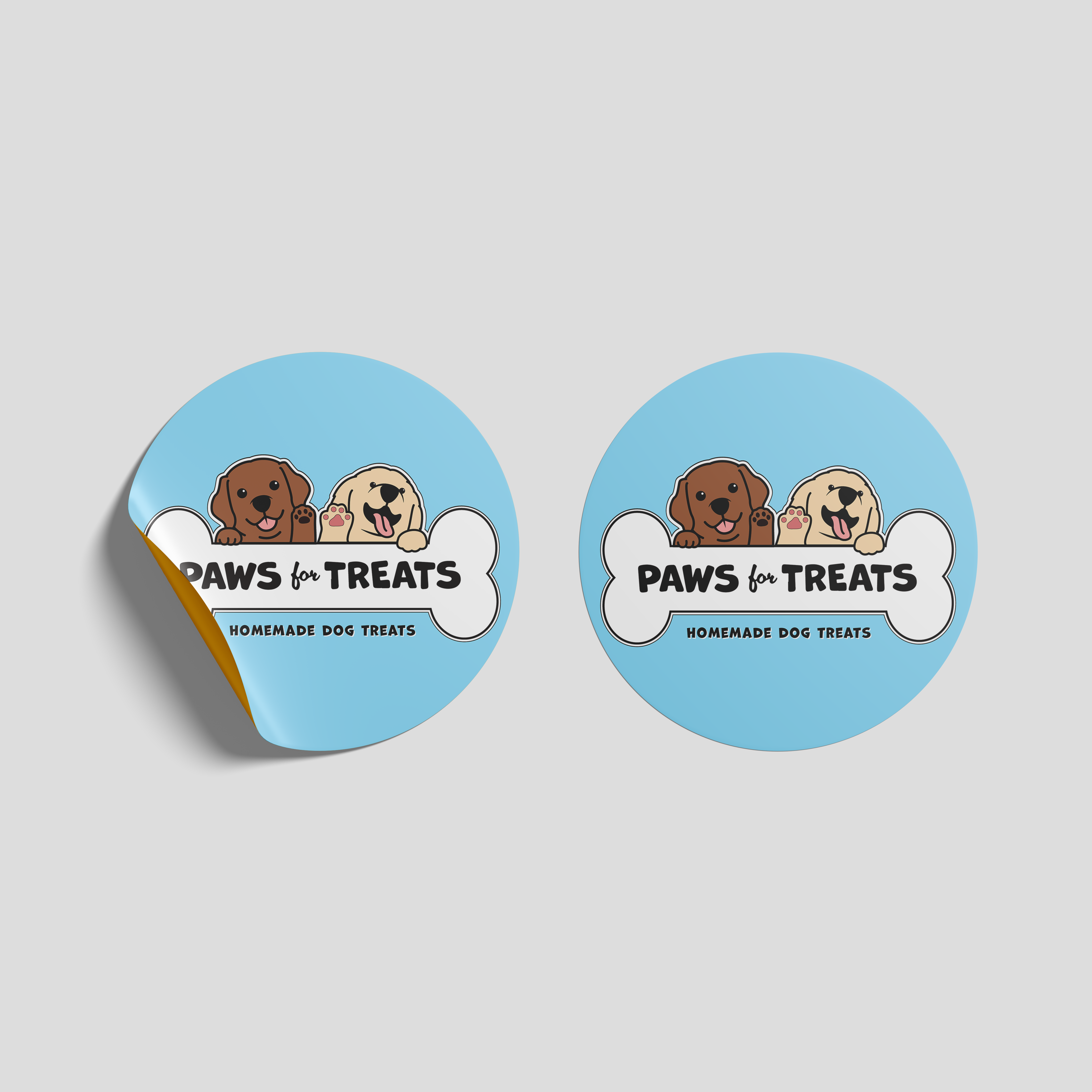 Two light blue, circular stickers. Sticker reads 'Paws for Treats homemade dog treats'. Text is written on top of a bone, which 2 smiling dogs peek over.